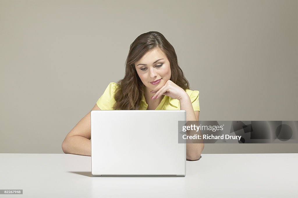 Young businesswoman sitting at desk using laptop