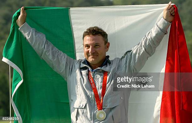 Francesco D'Aniello of Italy holds up the Italian flag after winning the silver medal in the men's double trap held at the Beijing Shooting Range...