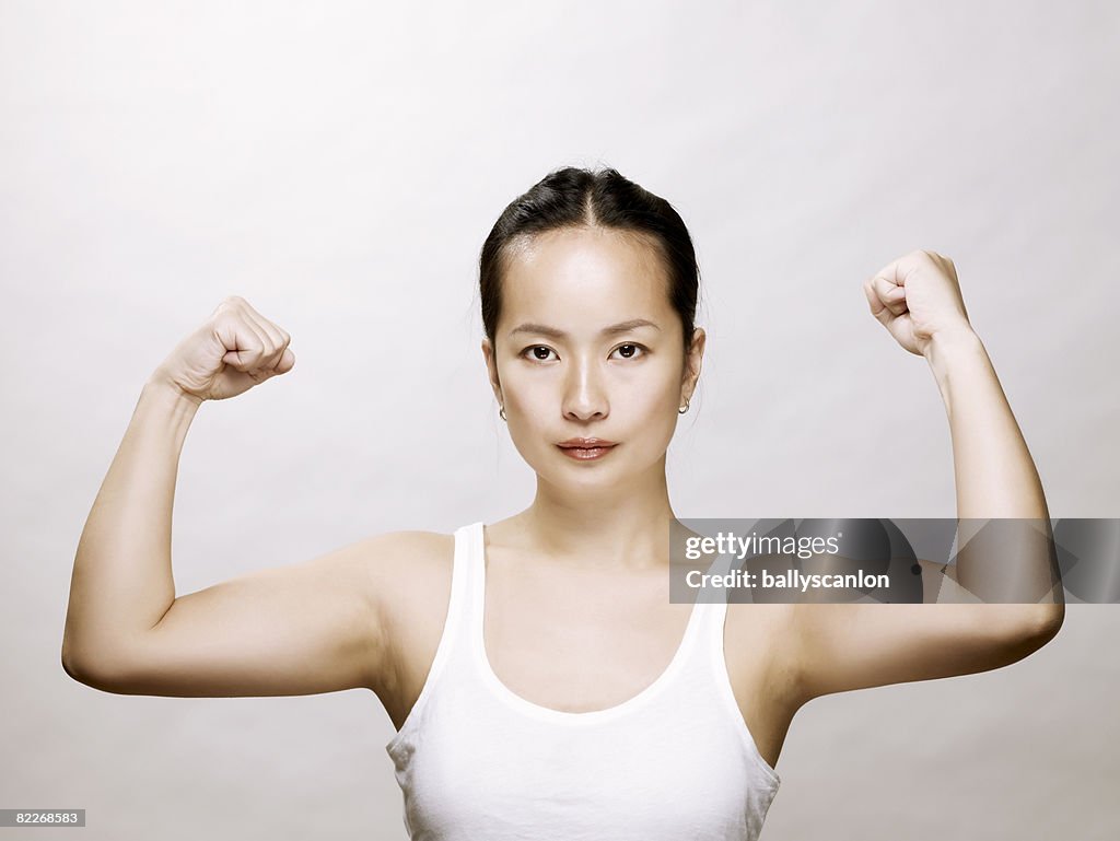 Young asian woman flexing her muscles