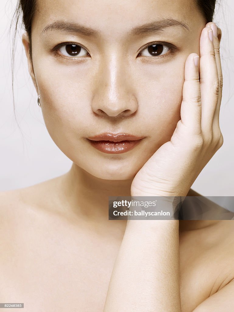 Young asian woman touching her face with her hand