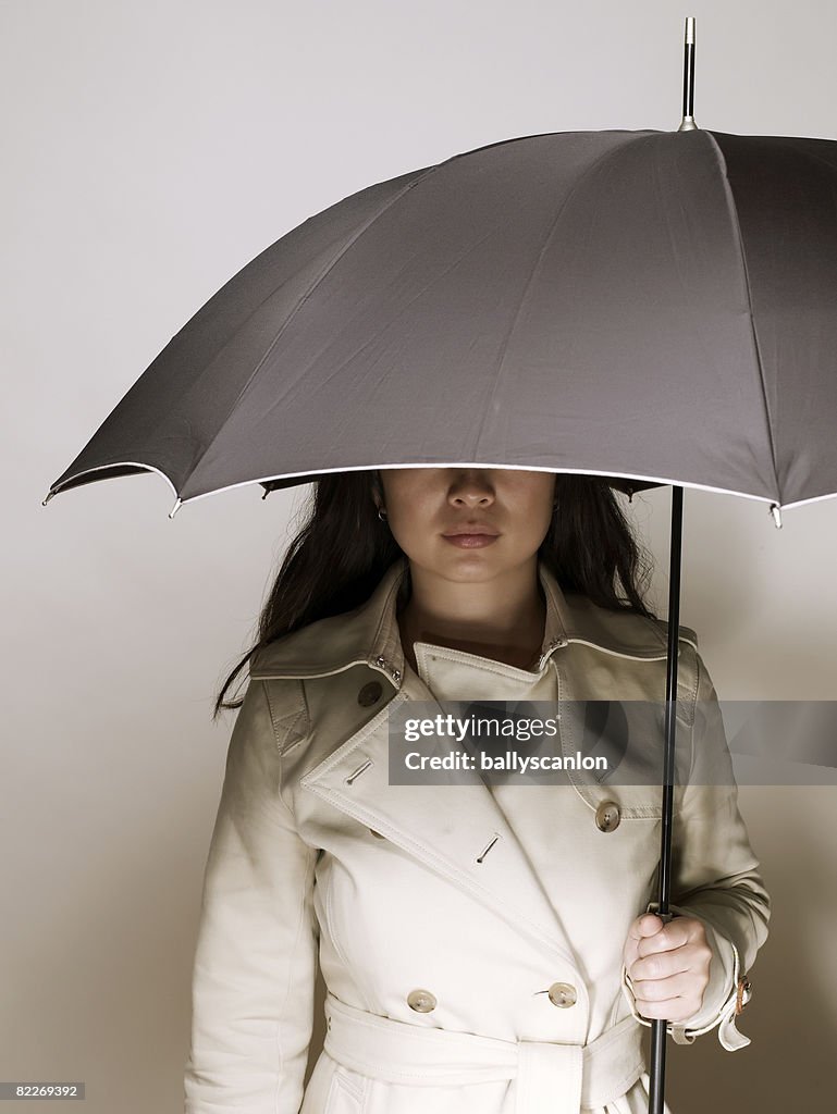 Young asian woman in raincoat, holding umbrella
