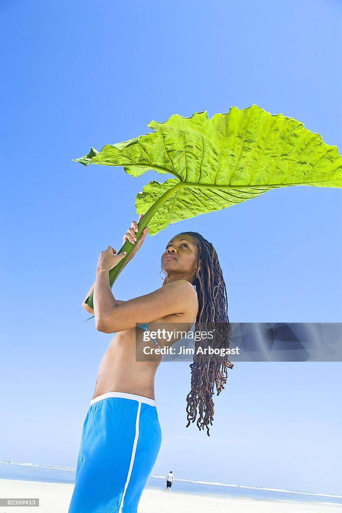 Women holds leaf for shade.