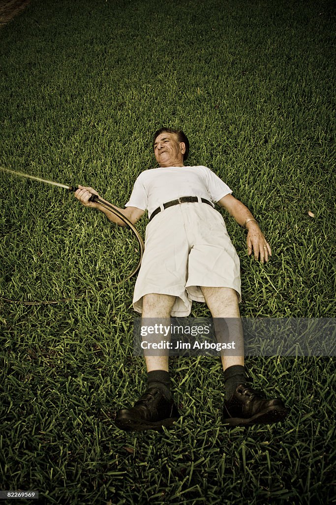 Man with hose lying on ground