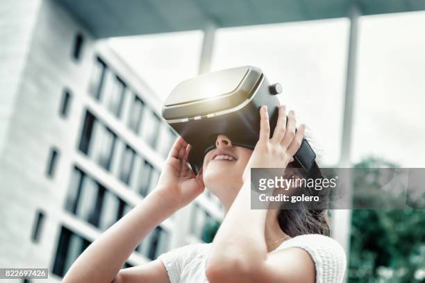 adolescente avec simulateur de réalité virtuelle en levant - casques réalité virtuelle photos et images de collection