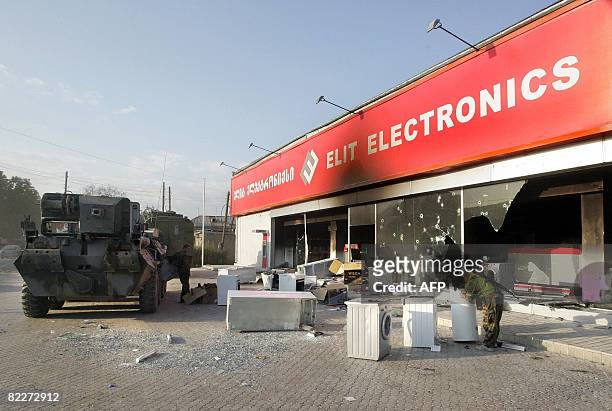 Picture taken on August 11 shows a looter looking at a washing mashine near a shop destroyed by fightint in the South Ossetian capital Tskhinvali....