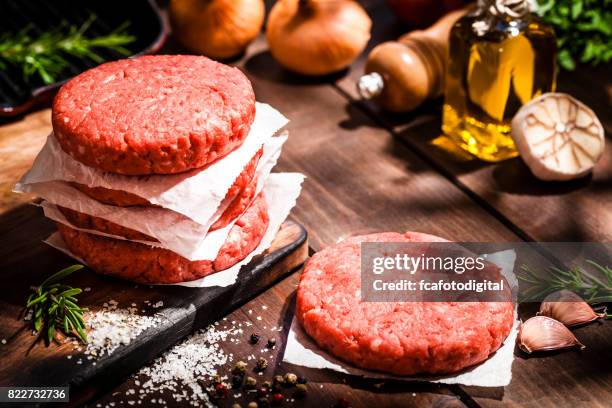 rauwe hamburger pasteitjes op rustieke houten tafel - burgers stockfoto's en -beelden