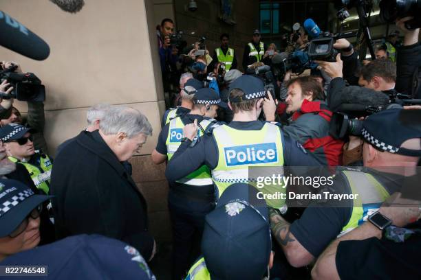 Cardinal Pell walks with a heavy Police guard from his barristers Robert Richter office to the Melbourne Magistrates' Court on July 26, 2017 in...