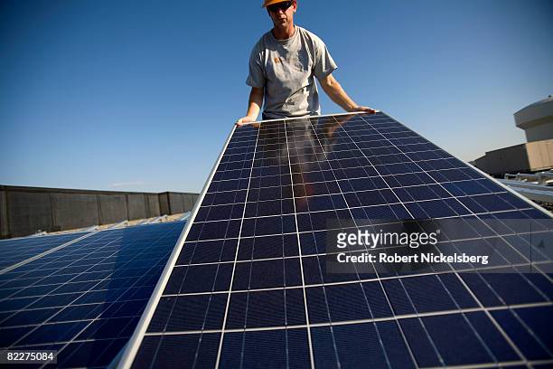 Employees of SunEdison install photovoltaic solar panels on the roof of a Kohl's Department Store on July 15, 2008 in Westhampton, New Jersey....