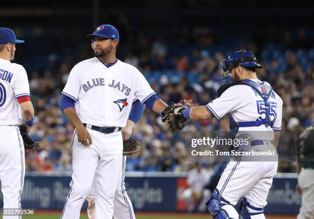 Cesar Valdez of the Toronto Blue Jays is congratulated by Russell Martin as he exits the game in the seventh inning during MLB game action against...