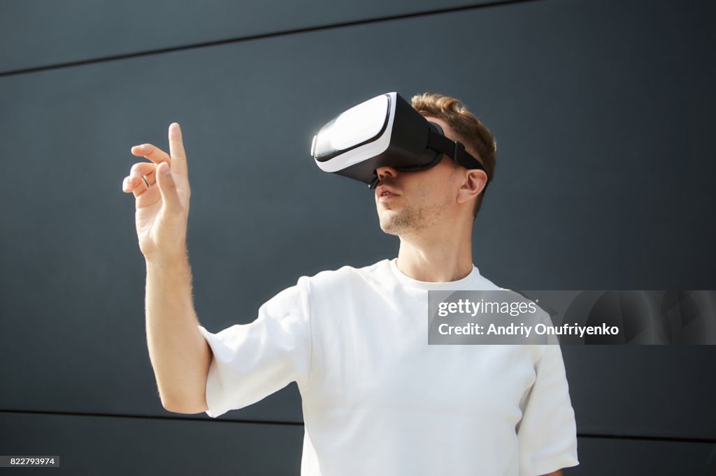 Excited man wearing VR glasses outdoors