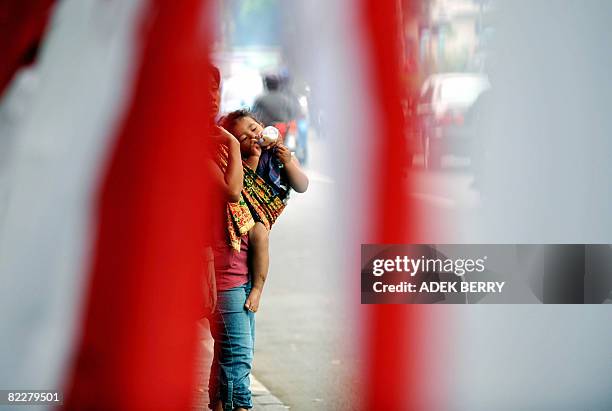 Woman cradling a child waits as she offers "jockey" service - someone who rides in a car so it can meet the quota of three people - to motorists in...