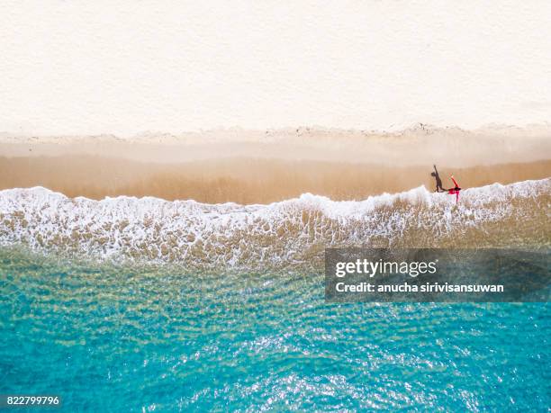 people wearing red shirts walking footprints on the beach white with blue sea waves , aerial view . - top view stairs photos et images de collection