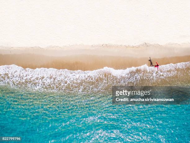 people wearing red shirts walking footprints on the beach white with blue sea waves , aerial view . - paesaggio urbano foto e immagini stock