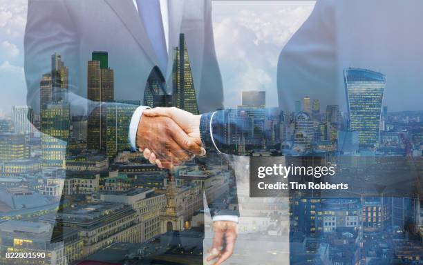 two people shaking hands with london skyline - negócios internacionais - fotografias e filmes do acervo