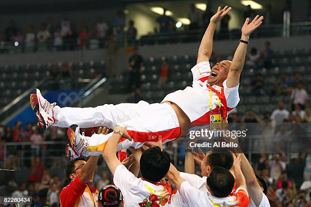 Coach Gao Jian of the Chinese women's gymnastics team is lifted up after China won the artistic gymnastics team event at the National Indoor Stadium...