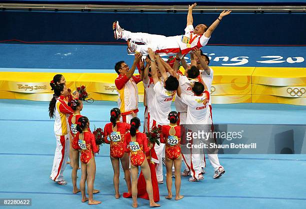 Coach Gao Jian of the Chinese women's gymnastics team is lifted into the air as the team celebrates after winning the artistic gymnastics team event...