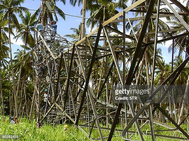 Workers, escorted by armed soldiers and police, repair the sabotaged electricity tower of Transco, a state-owned power transmission firm in Kauswagan...