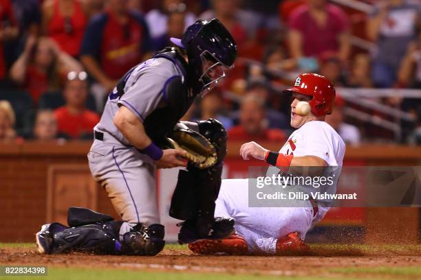 Harrison Bader of the St. Louis Cardinals scores the game-winning run ahead of the throw to Ryan Hanigan of the Colorado Rockies in the ninth inning...