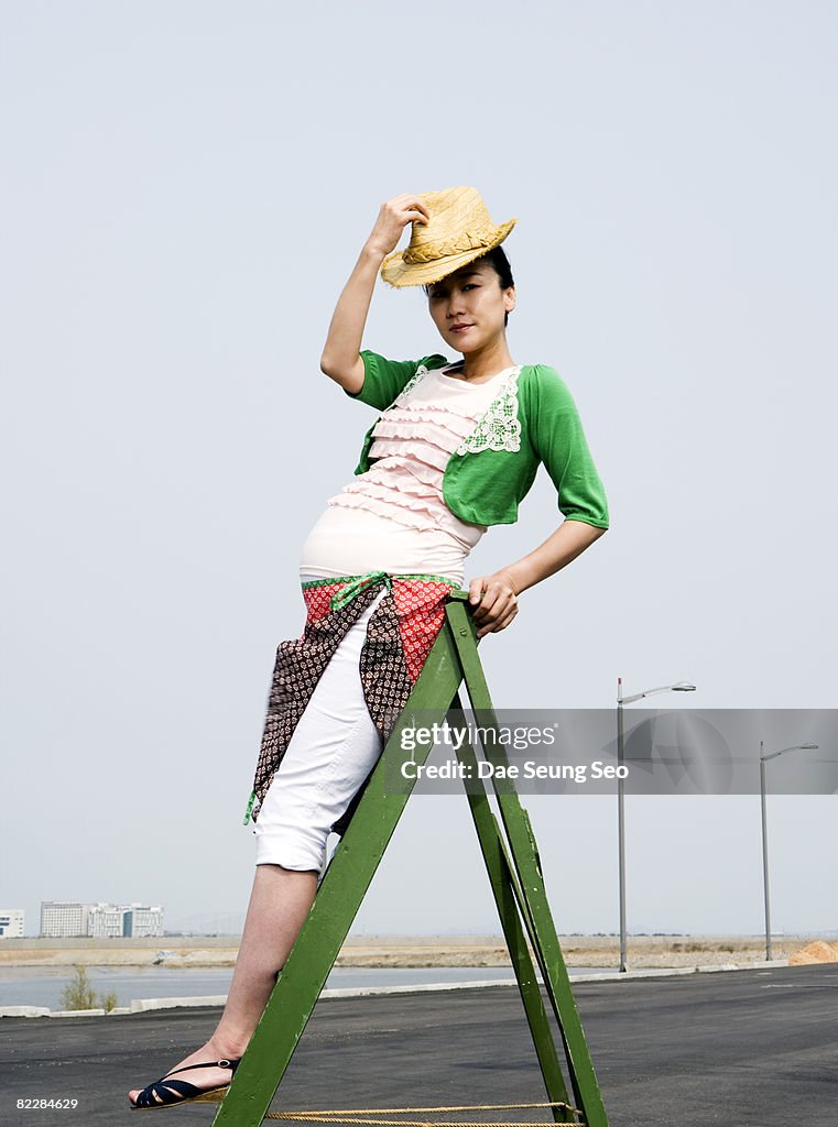 Pregnant woman on ladder with hat