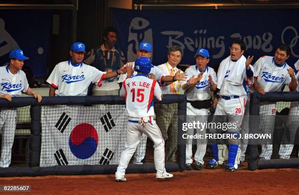 South Korea's Lee Yongkyu high-fives coaches and players in the dugout after scoring off a wild pitch by US pitcher Brandon Knight in the third...