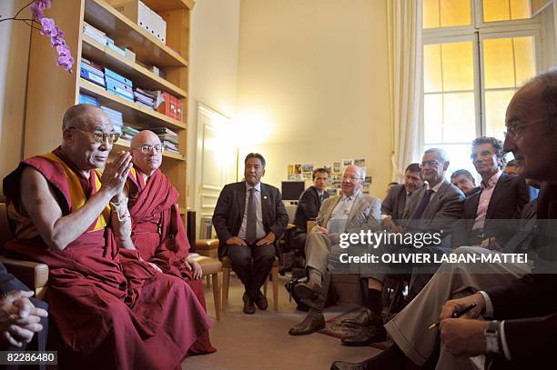 The Dalai Lama salutes lawmakers next to his French interpreter Matthieu Ricard during a meeting at the French senate, on August 13, 2008 in Paris....