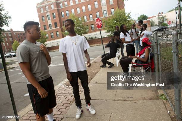 Johnathon Carrington left, greets a friend in the Sursum Corda neighborhood, near the apartment where he grew up and currently lives with his family,...