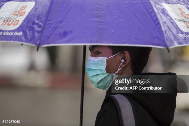 Man wears a face mask whilst waiting for a bus in Yangon on July 26, 2017. Two people, including a pregnant woman, have died from swine flu in Yangon...