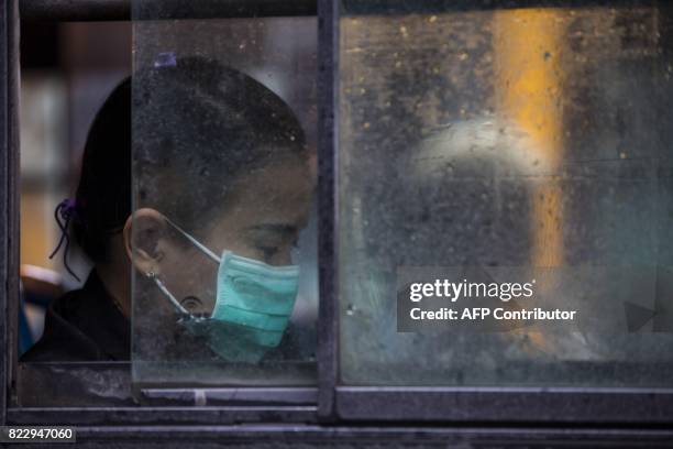 Woman wears a face mask whilst taking a bus in Yangon on July 26, 2017. Two people, including a pregnant woman, have died from swine flu in Yangon...