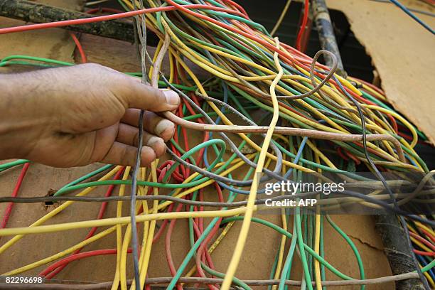 Man untangles electric cables that feed an apartment complex from a private generator in a neighbourhood in Baghdad on August 12, 2008. The power...