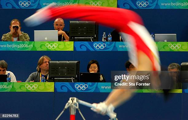 Kohei Uchimura of Japan competes on the bar exercise in front of the press tribune during the men's individual all-around final in the artistic...