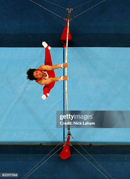 Hiroyuki Tomita of Japan competes on the high bar in the men's individual all-around artistic gymnastics final at the National Indoor Stadium during...