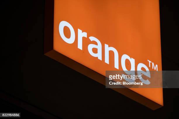 An illuminated logo hangs inside an Orange SA mobile phone store in Blagnac near Toulouse, France, on Wednesday, July 26, 2017. Orange is looking for...