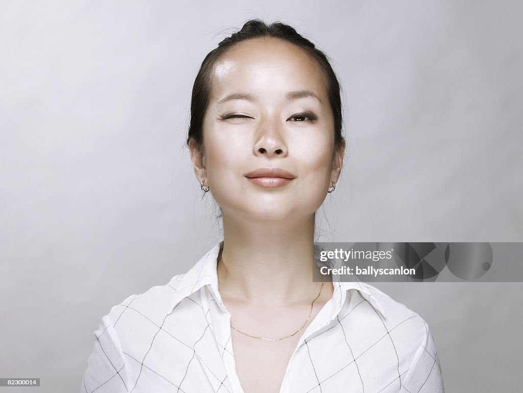 Young Asian woman, winking at camera.