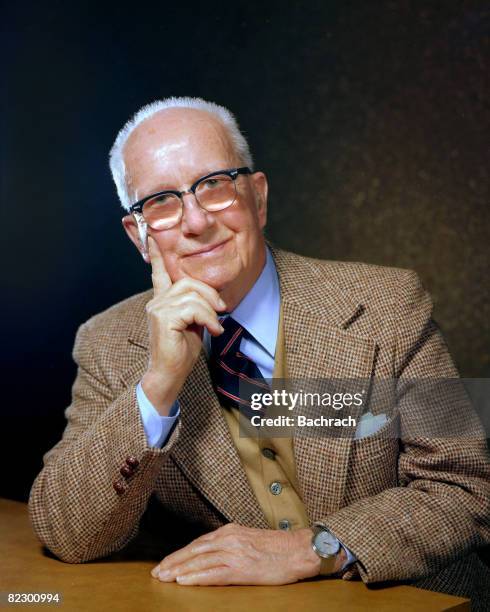 Portrait of American architect, inventor and futurist Buckminster Fuller as he sits at a table with his hand on his chin, Boston, Massachussetts,...