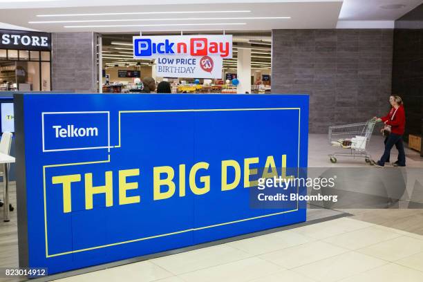 Shoppers push a cart past an advertisement for Telkom SA SOC Ltd. Outside a Pick n Pay Stores Ltd. Supermarket in a retail mall in Johannesburg,...