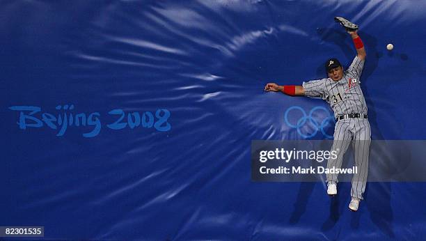 Left fielder Masahiko Morino of Japan hits the outfield wall while attempting to catch a fly ball against the Chinese Taipei during their preliminary...