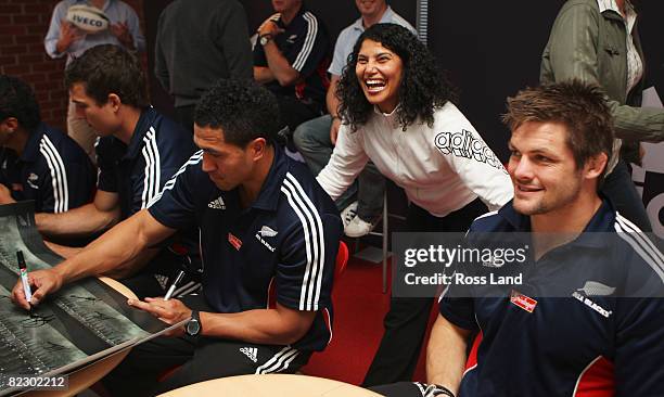 Richie McCaw poses for a photograph with a staff member as Anthony Boric and Mils Muliaina sign posters during a visit to the adidas factory...