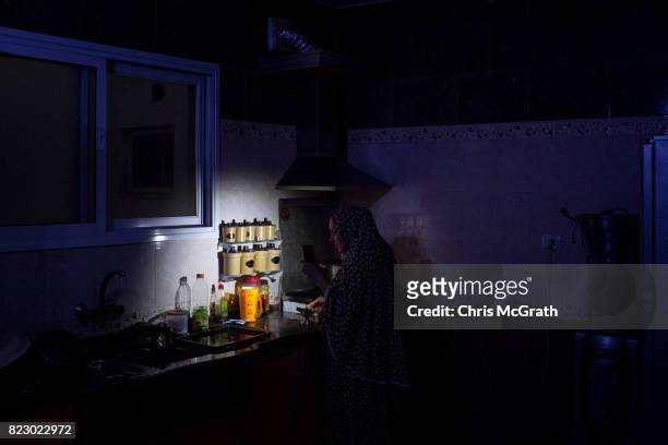 Maha Zant makes tea by cell phone light at her home in the Al-Zahra district on July 23, 2017 in Gaza City, Gaza. For the past ten years Gaza...