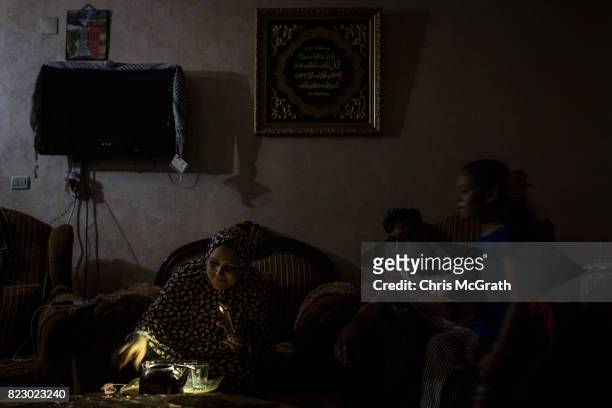 Maha Zant prepares tea for her husband Rami by cell phone light at her home in the Al-Zahra district on July 23, 2017 in Gaza City, Gaza. For the...
