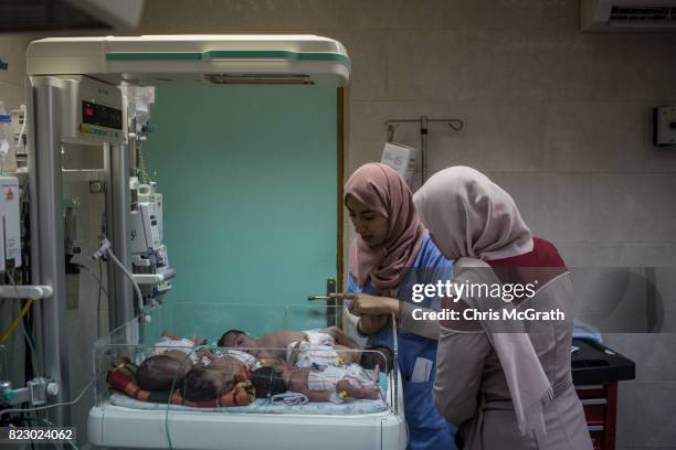 Nurse talks with a family member next to newborn babies suffering from various medical complications hooked up to medical equipment in the neonatal...