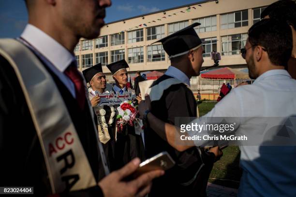 University students from Al-Azhar University celebrate and pose for photos ahead of the start of their graduation ceremony on July 18, 2017 in Gaza...