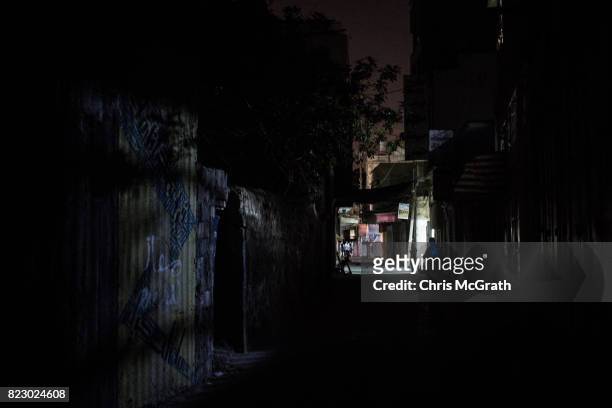 Man is seen illuminated by his cell phone as he walks in a darkened downtown street on July 22, 2017 in Gaza City, Gaza. For the past ten years Gaza...