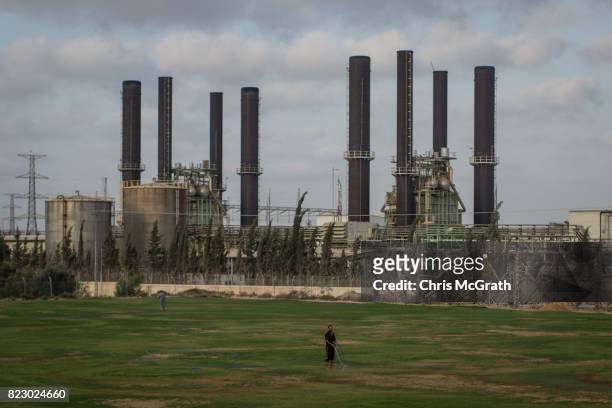 Man is seen watering a football field in front of Gaza's only power plant in the Nusseirat district on July 19, 2017 in Gaza City, Gaza. For the past...