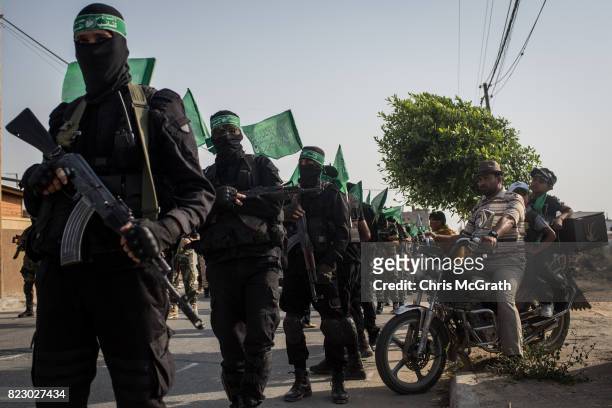 People watch on as Palestinian Hamas militants take part in a military show in the Bani Suheila district on July 20, 2017 in Gaza City, Gaza. For the...