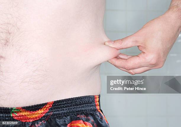 middle aged man pinching fat on his waistline - ugly fat guy stock pictures, royalty-free photos & images