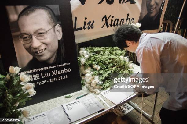 Man writing his message in the memorial book for Liu Xiaobo. Residents of Hong Kong hosted a vigil service outside the Chinese Liaison Office of Hong...