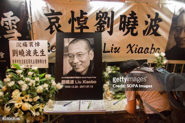 Man writing his message in the memorial book for Liu Xiaobo. Residents of Hong Kong hosted a vigil service outside the Chinese Liaison Office of Hong...