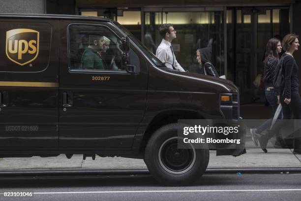 Pedestrians walk past a A United Parcel Service Inc. Delivery van on a street in New York, U.S, on Monday, July 24, 2017. United Parcel Service Inc....