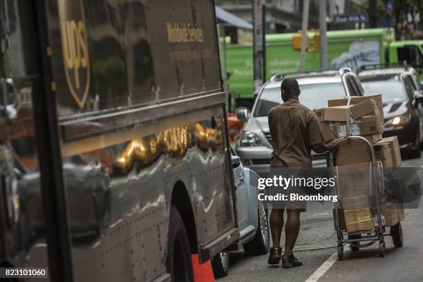 United Parcel Service Inc. Delivery driver pushes a dolly of packages to be delivered on a street in New York, U.S, on Monday, July 24, 2017. United...
