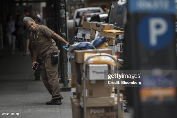 United Parcel Service Inc. Delivery driver pulls a dolly of packages to be delivered onto a sidewalk in New York, U.S, on Monday, July 24, 2017....